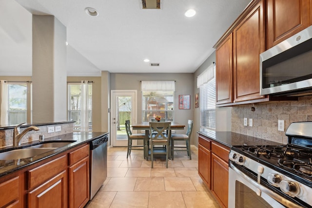 kitchen featuring appliances with stainless steel finishes, visible vents, a sink, and dark stone countertops