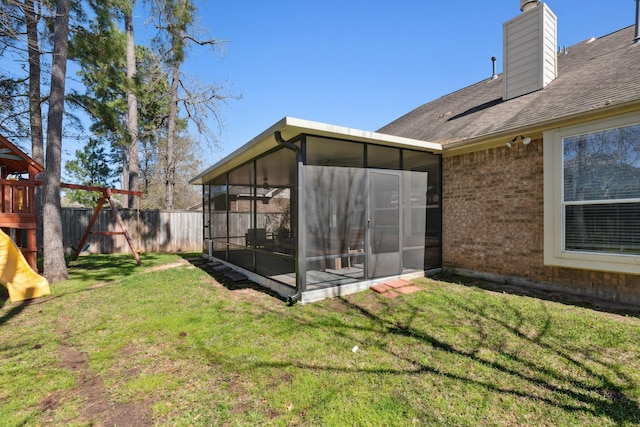 view of yard with a sunroom, a playground, and fence