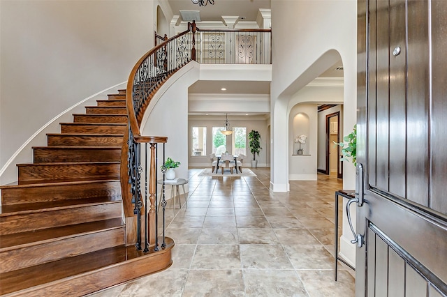 entrance foyer featuring stairs, ornamental molding, a towering ceiling, and baseboards