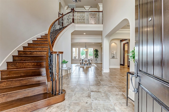 entryway with arched walkways, a high ceiling, crown molding, stairs, and baseboards