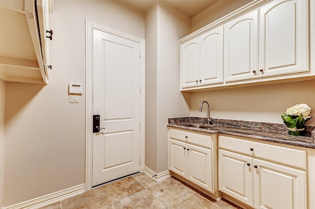 interior space featuring baseboards, dark stone counters, and a sink