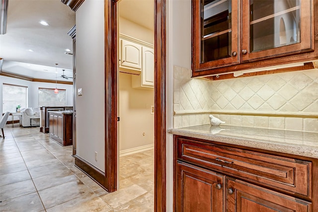 kitchen with glass insert cabinets, light tile patterned floors, backsplash, and light stone countertops