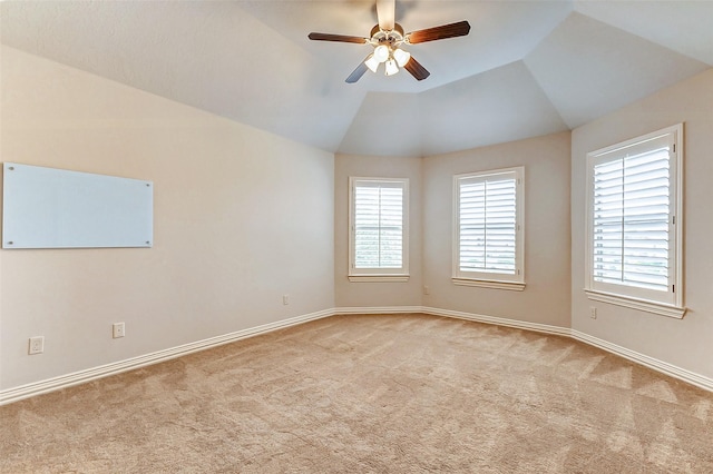 empty room with lofted ceiling, plenty of natural light, a ceiling fan, and light colored carpet