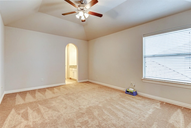 unfurnished room featuring light carpet, arched walkways, a ceiling fan, and lofted ceiling