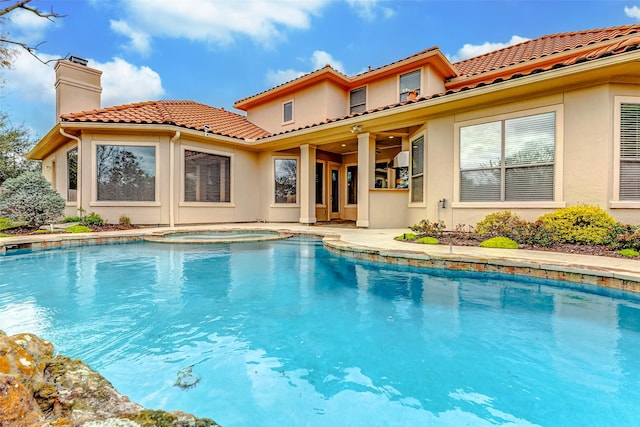 back of house featuring a tiled roof, a chimney, an outdoor pool, and stucco siding