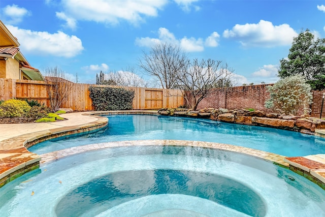 view of pool with a fenced backyard and a pool with connected hot tub