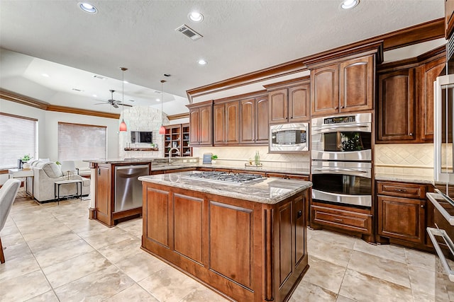 kitchen featuring a peninsula, a kitchen island, visible vents, appliances with stainless steel finishes, and light stone countertops