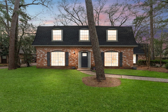 view of front property with a shingled roof, mansard roof, a lawn, and brick siding