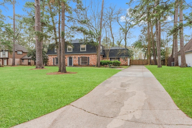 view of front of home with brick siding, driveway, a front lawn, and fence