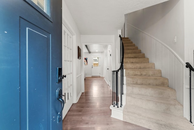 foyer featuring a wainscoted wall, stairway, and wood finished floors