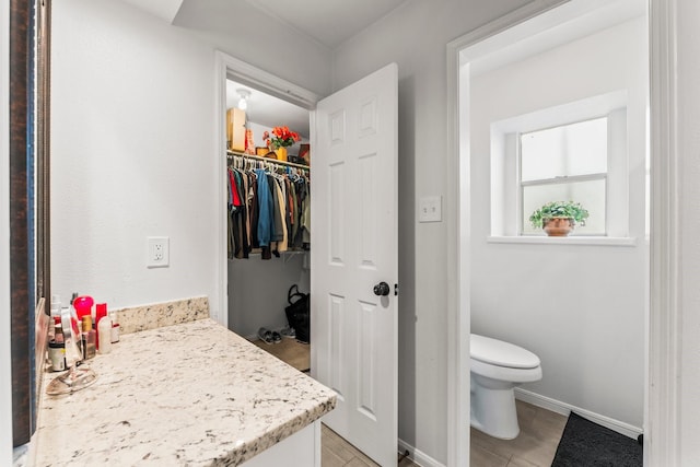 bathroom featuring baseboards, vanity, toilet, and tile patterned floors