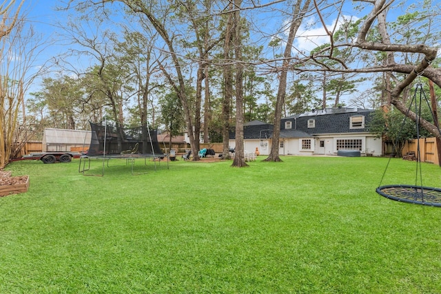 view of yard featuring a trampoline and fence