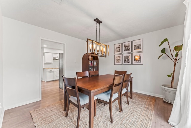 dining space featuring baseboards, a notable chandelier, and light wood-style floors