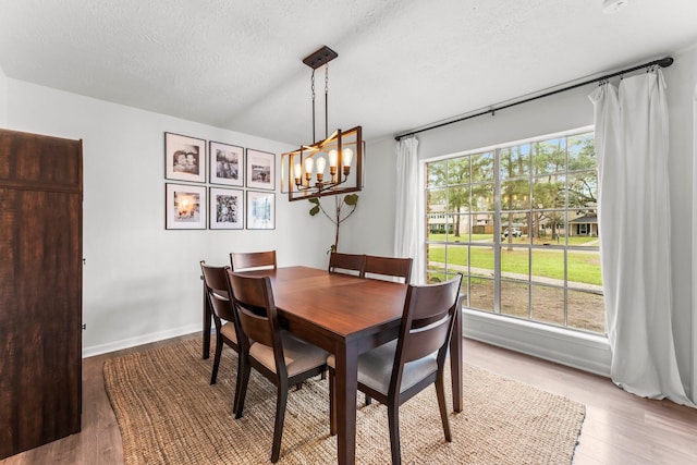 dining area with a chandelier, a textured ceiling, baseboards, and wood finished floors