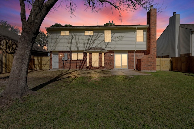 rear view of house featuring a patio area, fence, a lawn, and brick siding