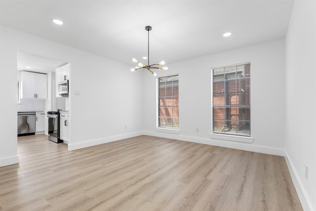 unfurnished dining area with light wood-style flooring, baseboards, and an inviting chandelier