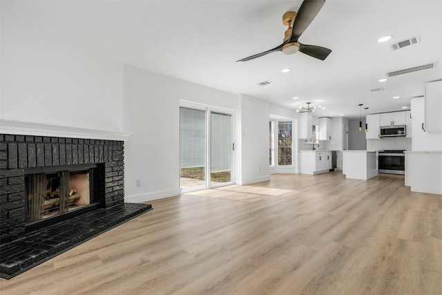 unfurnished living room featuring visible vents, a fireplace, and light wood finished floors