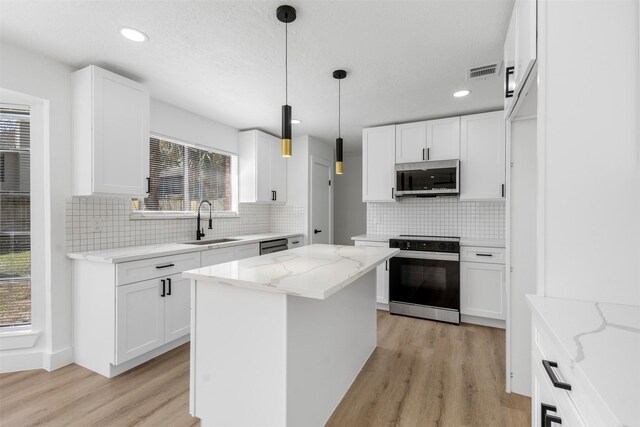 kitchen with a sink, visible vents, white cabinets, light wood-style floors, and appliances with stainless steel finishes