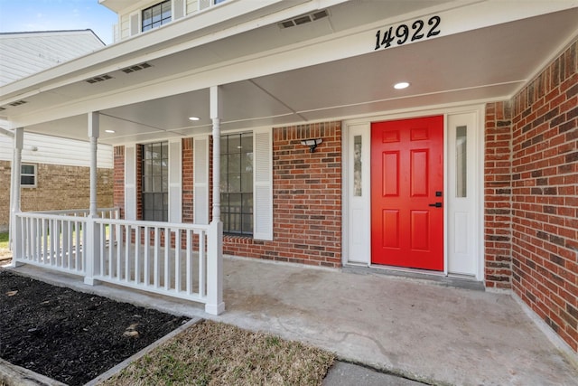 property entrance featuring covered porch and brick siding