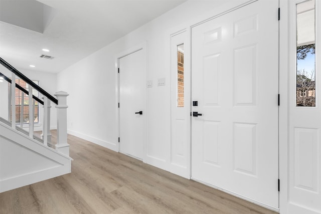 entrance foyer featuring visible vents, plenty of natural light, stairway, and wood finished floors