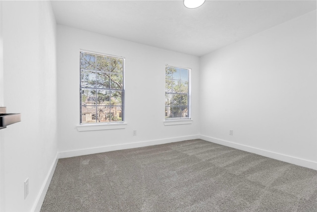 carpeted empty room featuring baseboards