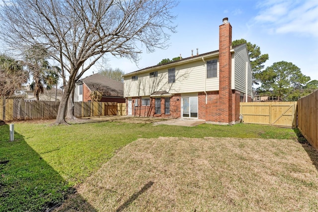 rear view of house featuring brick siding, a chimney, a fenced backyard, and a lawn