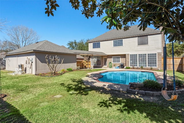 back of house featuring a yard, brick siding, fence, and a fenced in pool