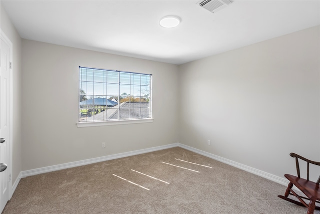 empty room with baseboards, visible vents, and carpet flooring