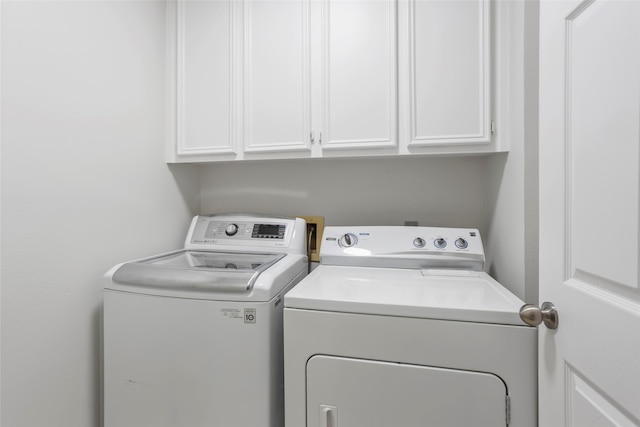 clothes washing area with washer and dryer and cabinet space