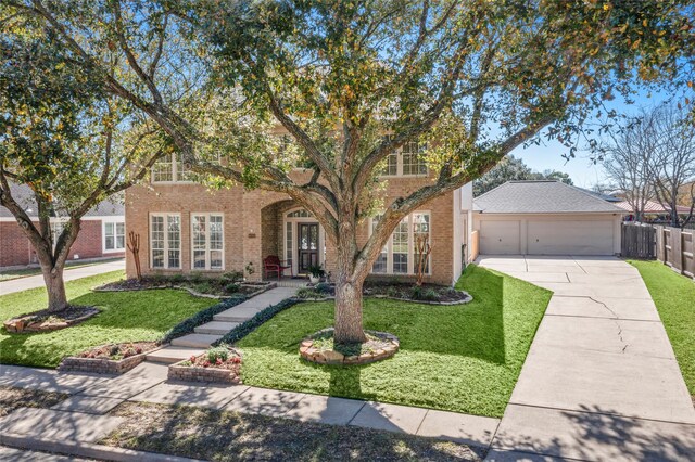 view of front facade with a front yard, brick siding, fence, and driveway