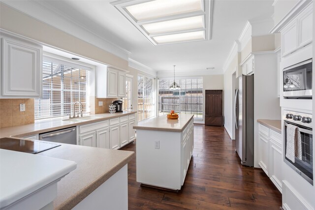 kitchen featuring crown molding, appliances with stainless steel finishes, a sink, and a center island