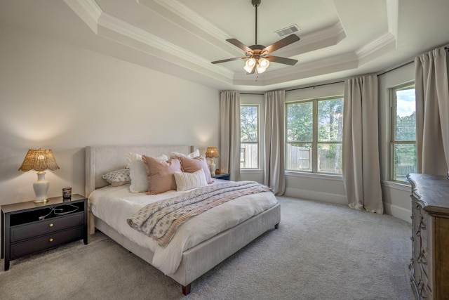 bedroom featuring a tray ceiling, light colored carpet, visible vents, and crown molding