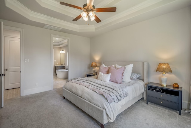 carpeted bedroom with crown molding, a raised ceiling, visible vents, ensuite bathroom, and baseboards