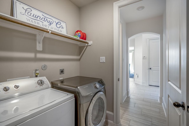 clothes washing area with laundry area, baseboards, arched walkways, and washer and clothes dryer