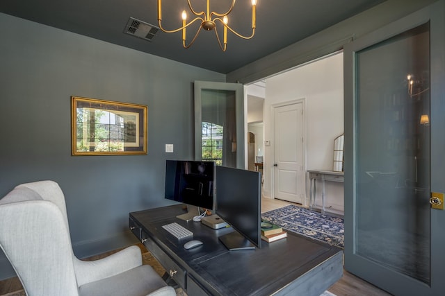 office space with visible vents, a notable chandelier, baseboards, and wood finished floors