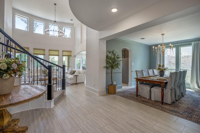 dining room featuring a healthy amount of sunlight, stairway, a chandelier, and arched walkways