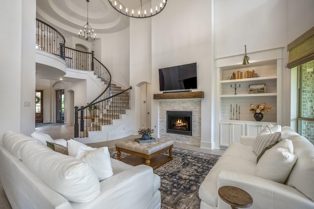 living room with arched walkways, a chandelier, a high ceiling, a fireplace, and stairway