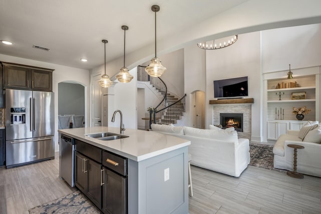 kitchen with visible vents, arched walkways, appliances with stainless steel finishes, open floor plan, and a sink