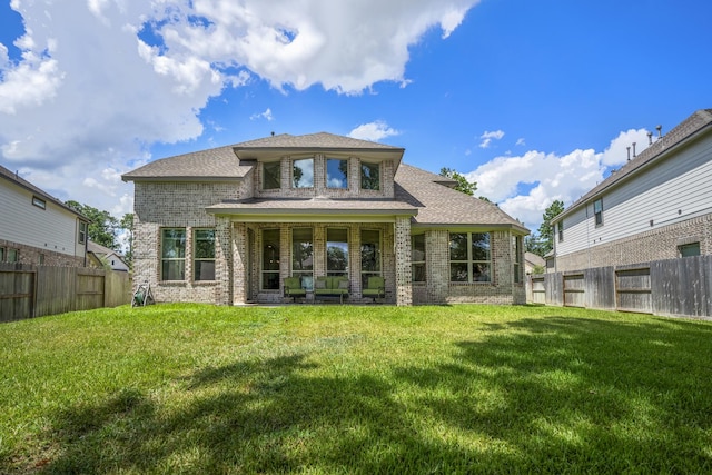 back of house with a fenced backyard, a lawn, and brick siding