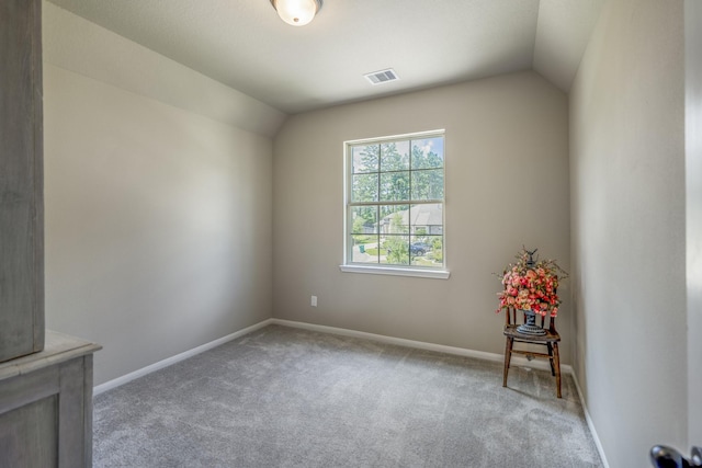 carpeted spare room featuring lofted ceiling, visible vents, and baseboards