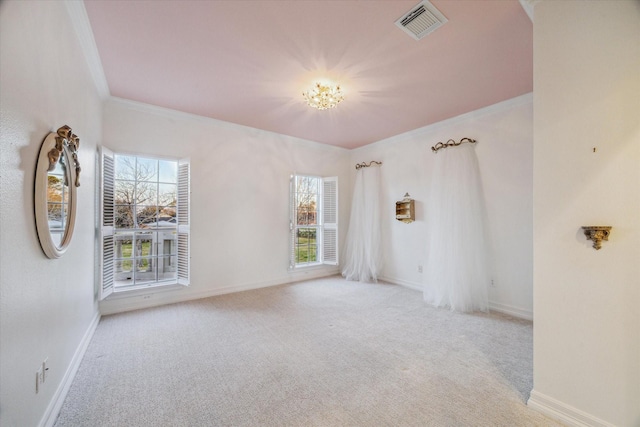 carpeted spare room featuring visible vents, baseboards, and crown molding