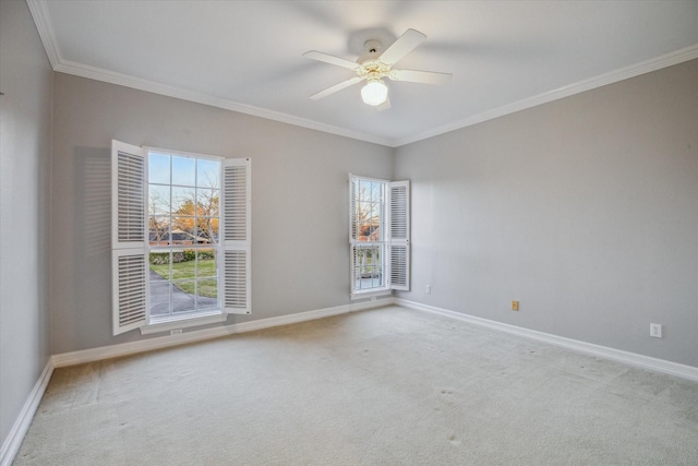 carpeted empty room featuring baseboards, a ceiling fan, and crown molding