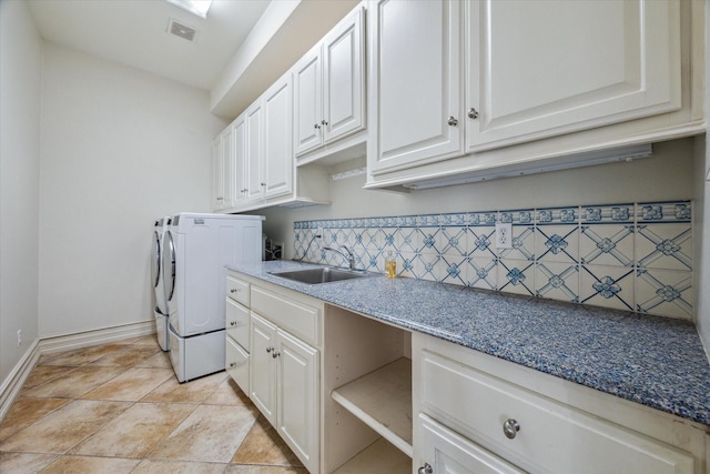 laundry area with baseboards, visible vents, cabinet space, separate washer and dryer, and a sink