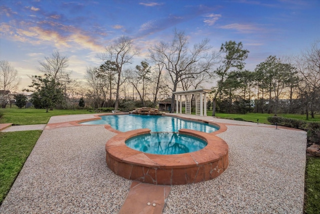 pool at dusk with an outdoor pool, an in ground hot tub, and a yard