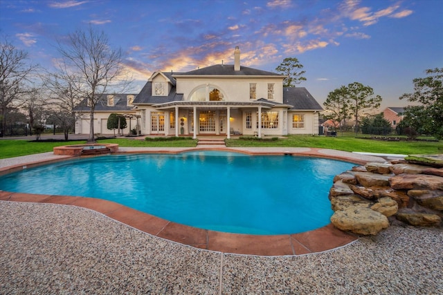 pool with an in ground hot tub, a lawn, and a patio