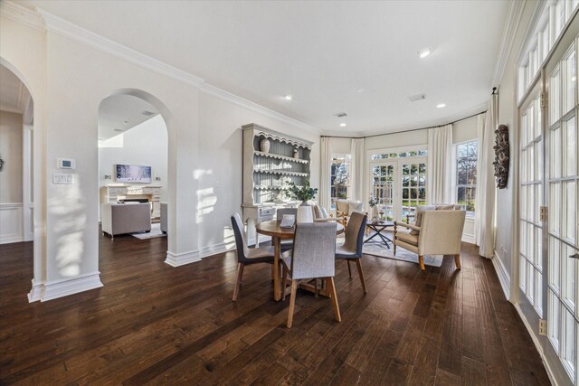 dining room featuring hardwood / wood-style floors, visible vents, arched walkways, ornamental molding, and french doors