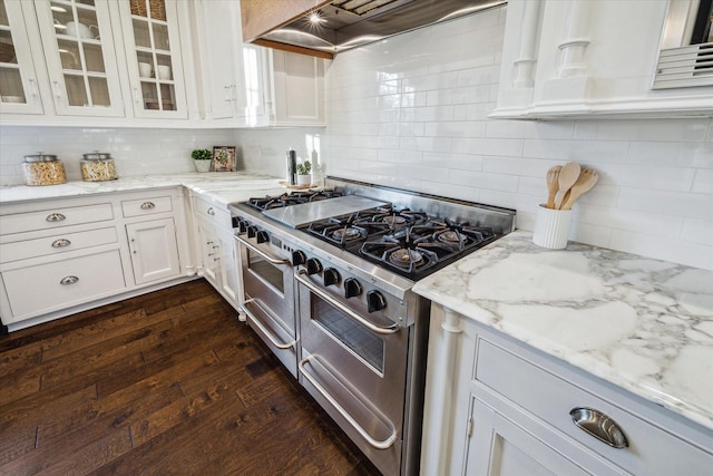 kitchen with dark wood finished floors, white cabinets, range with two ovens, glass insert cabinets, and extractor fan