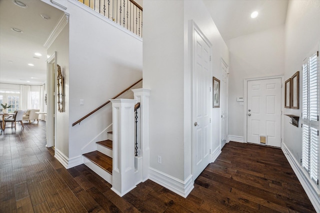 foyer entrance with baseboards, recessed lighting, stairs, hardwood / wood-style flooring, and a towering ceiling