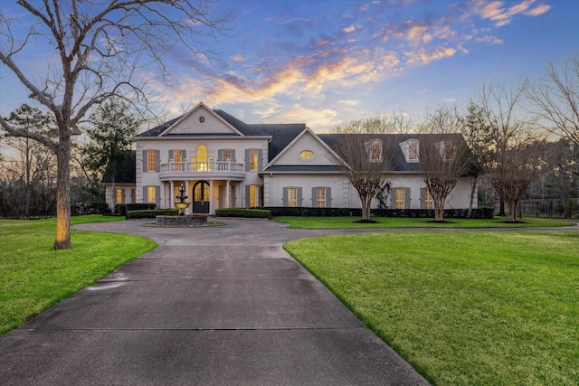 neoclassical / greek revival house with curved driveway, a balcony, and a front yard