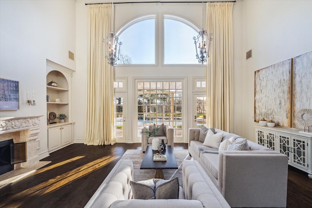 living room featuring visible vents, dark wood-type flooring, built in features, a high end fireplace, and a high ceiling